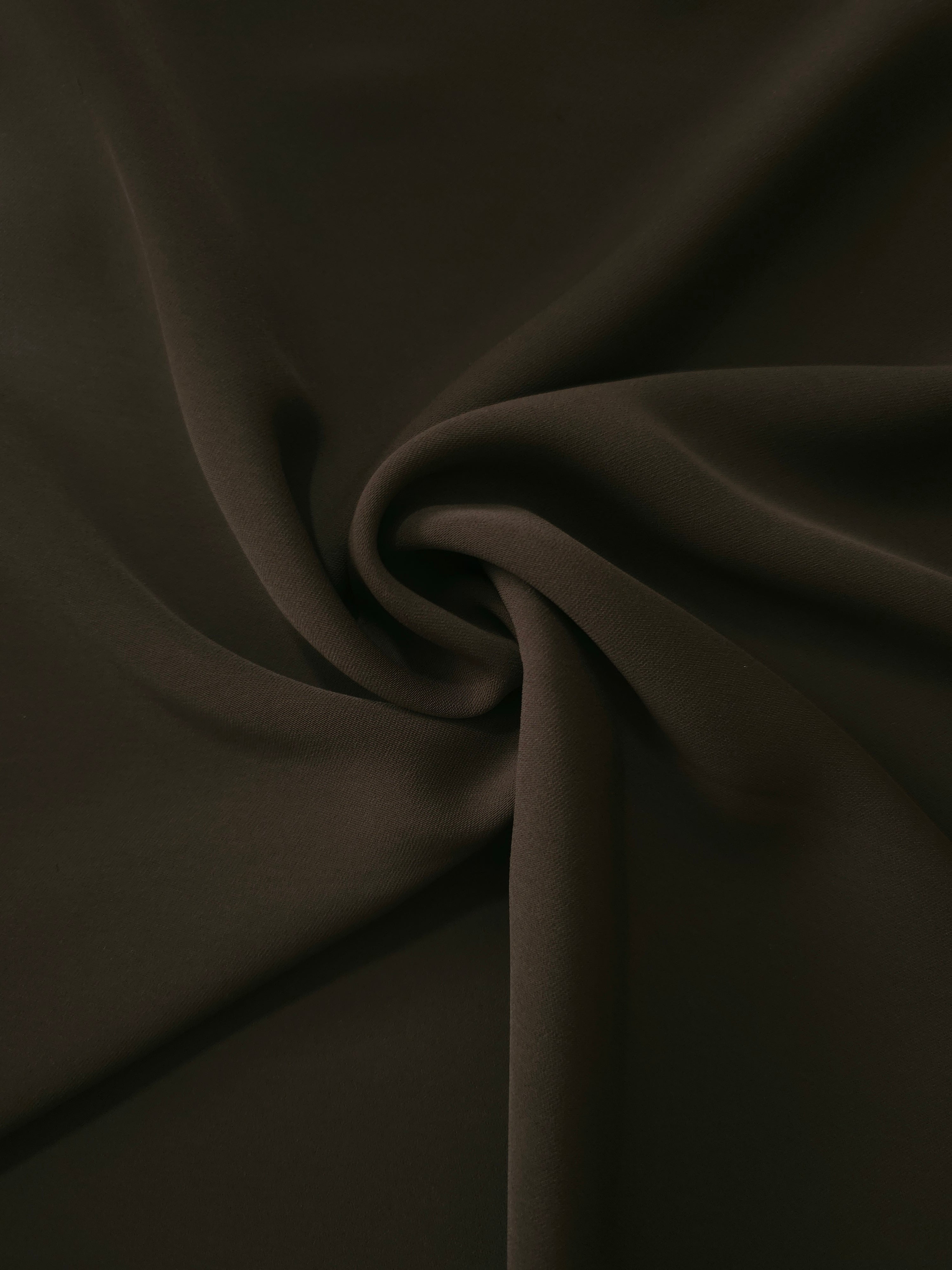 Swirled Ink Olive Black Silky Italian Crepe showing flowing movement in a swirl drape, versatile for kaftans, long skirts and fluid occasionwear.