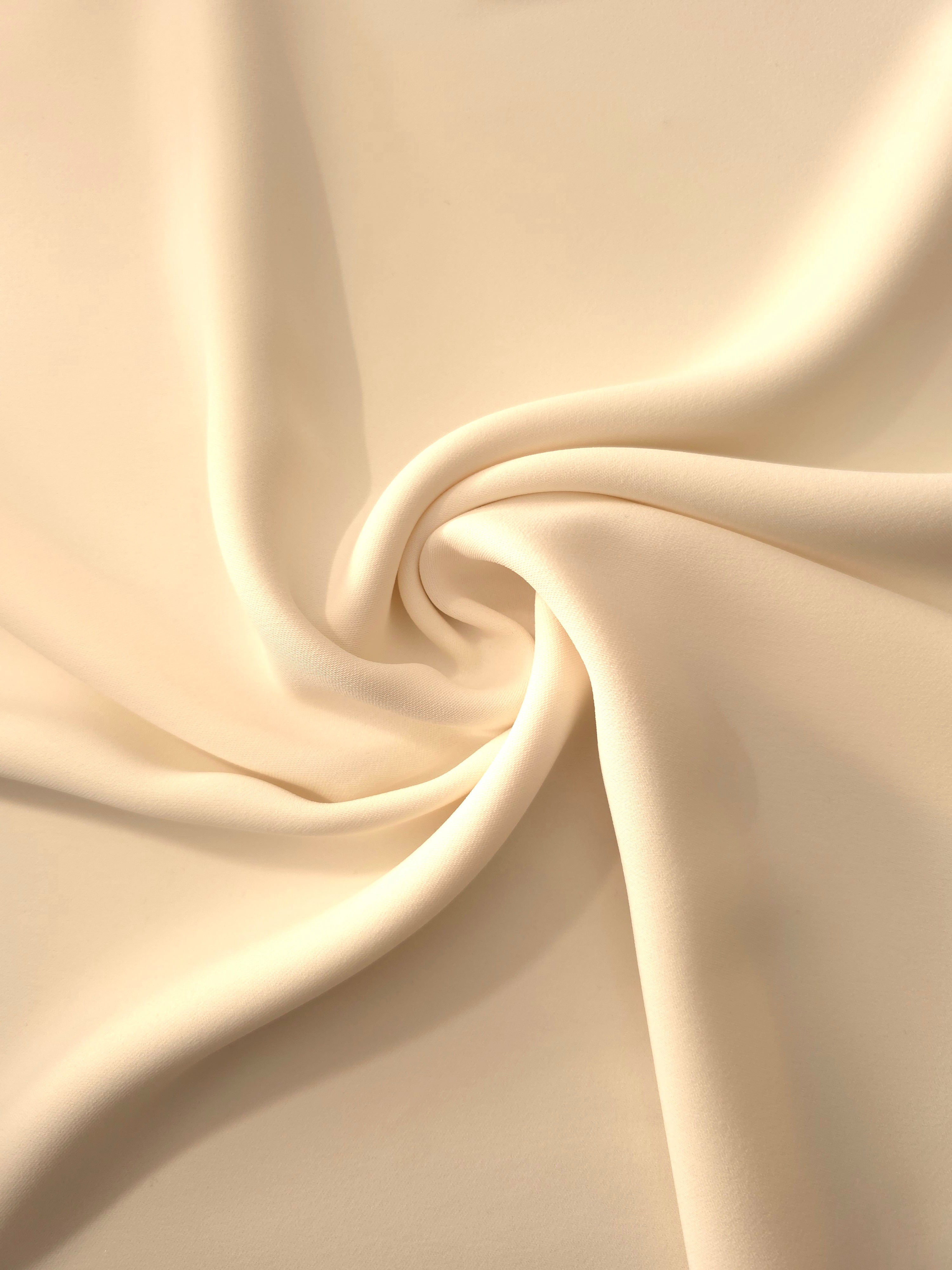 Swirled Oat Almond Cream Silky Italian Crepe showing flowing movement in a swirl drape, versatile for cocktail dresses, skirts and polished separates.