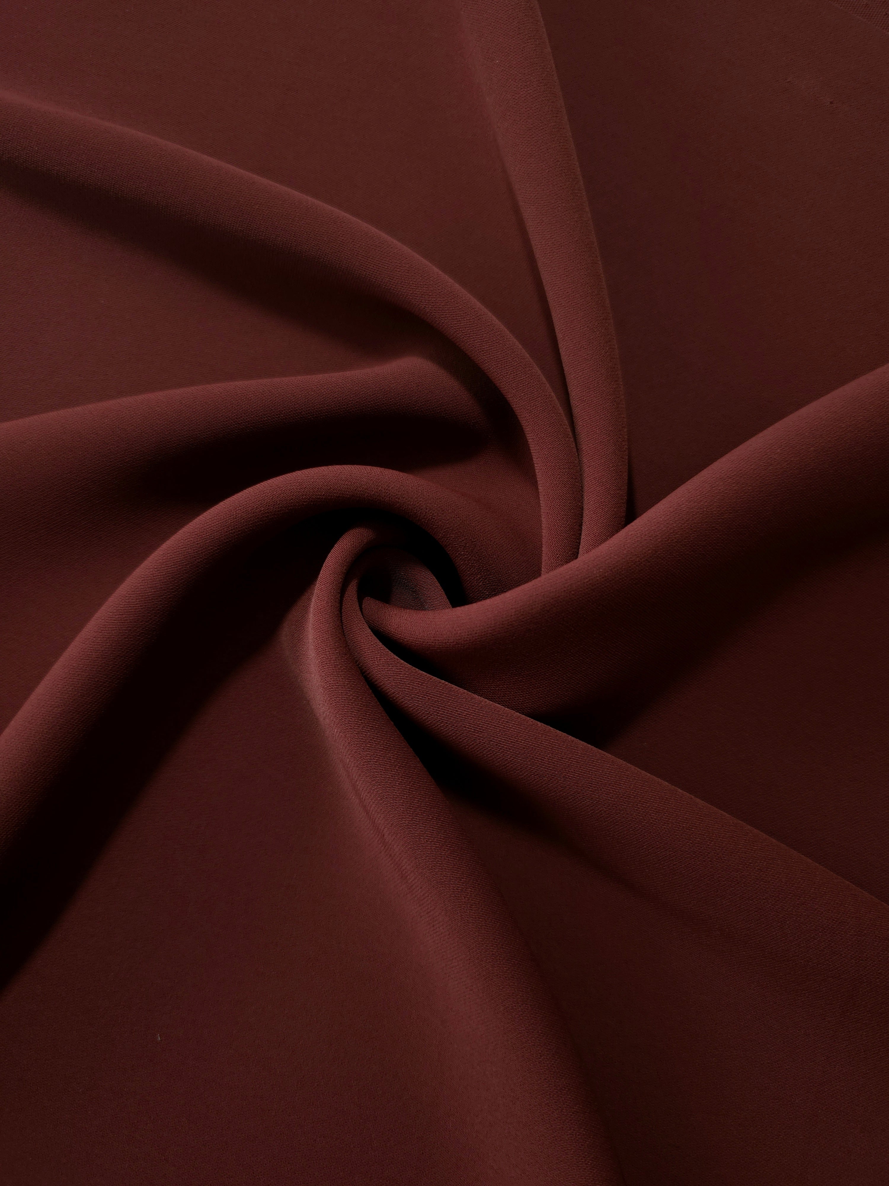 Swirled Russet Mahogany Silky Italian Crepe showing flowing movement in a swirl drape, versatile for formal gowns, abayas and special-occasion skirts.