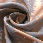 A tight fold in the copper animal print satin, the blue-grey patches breaking up unevenly at the crease