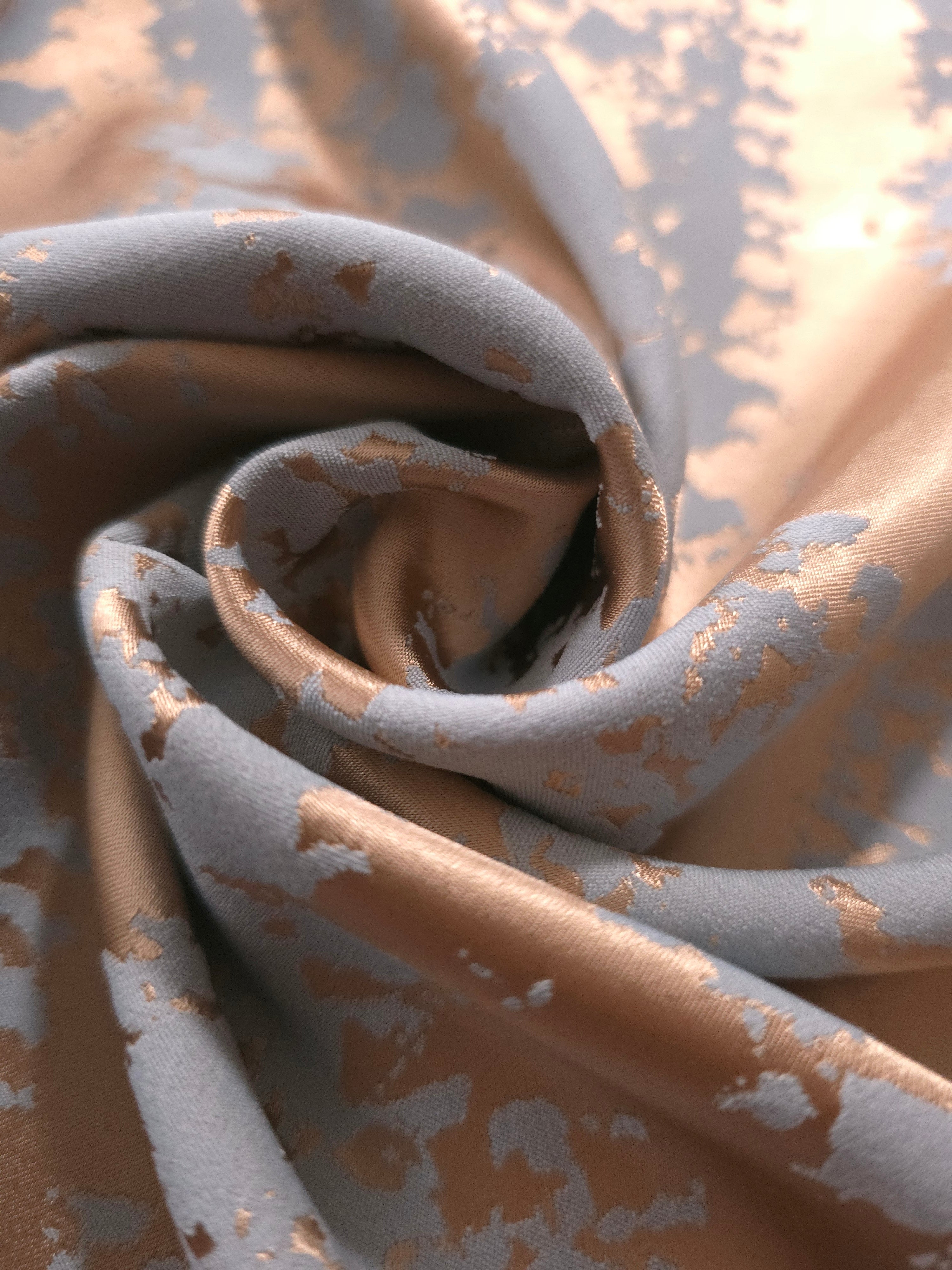 A tight fold in the copper animal print satin, the blue-grey patches breaking up unevenly at the crease