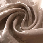 A soft crease in the taupe satin, the mottled pattern only emerging where light catches the fabric directly