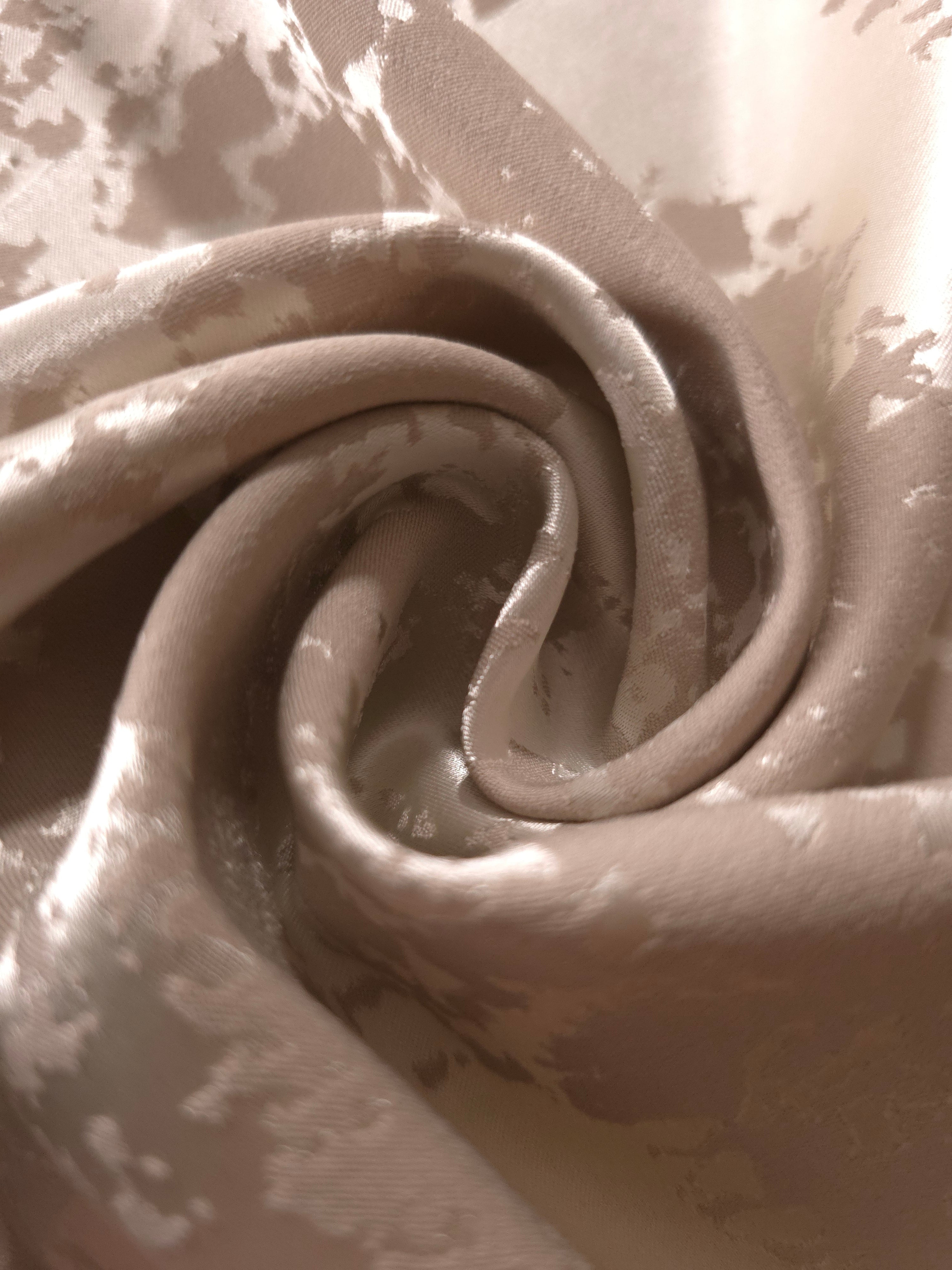 A soft crease in the taupe satin, the mottled pattern only emerging where light catches the fabric directly