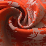 A tight fold in the burnt orange satin, the grey-mauve patches breaking sharply at the crease