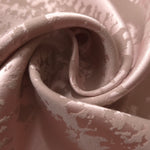 A gentle fold in the mauve-rose satin, the mottled pattern catching light unevenly across the crease