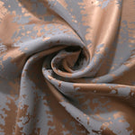 Copper animal print satin draped to show its glossy movement against the mottled blue-grey pattern