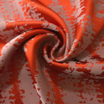 Burnt orange animal print satin draped to catch the light, the high-contrast pattern visible across the fold