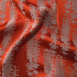 Burnt orange satin folded over, the grey-mauve mottled pattern standing out sharply against the bold base