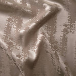 Taupe-beige satin folded gently, the animal print pattern reading mostly through subtle tonal sheen