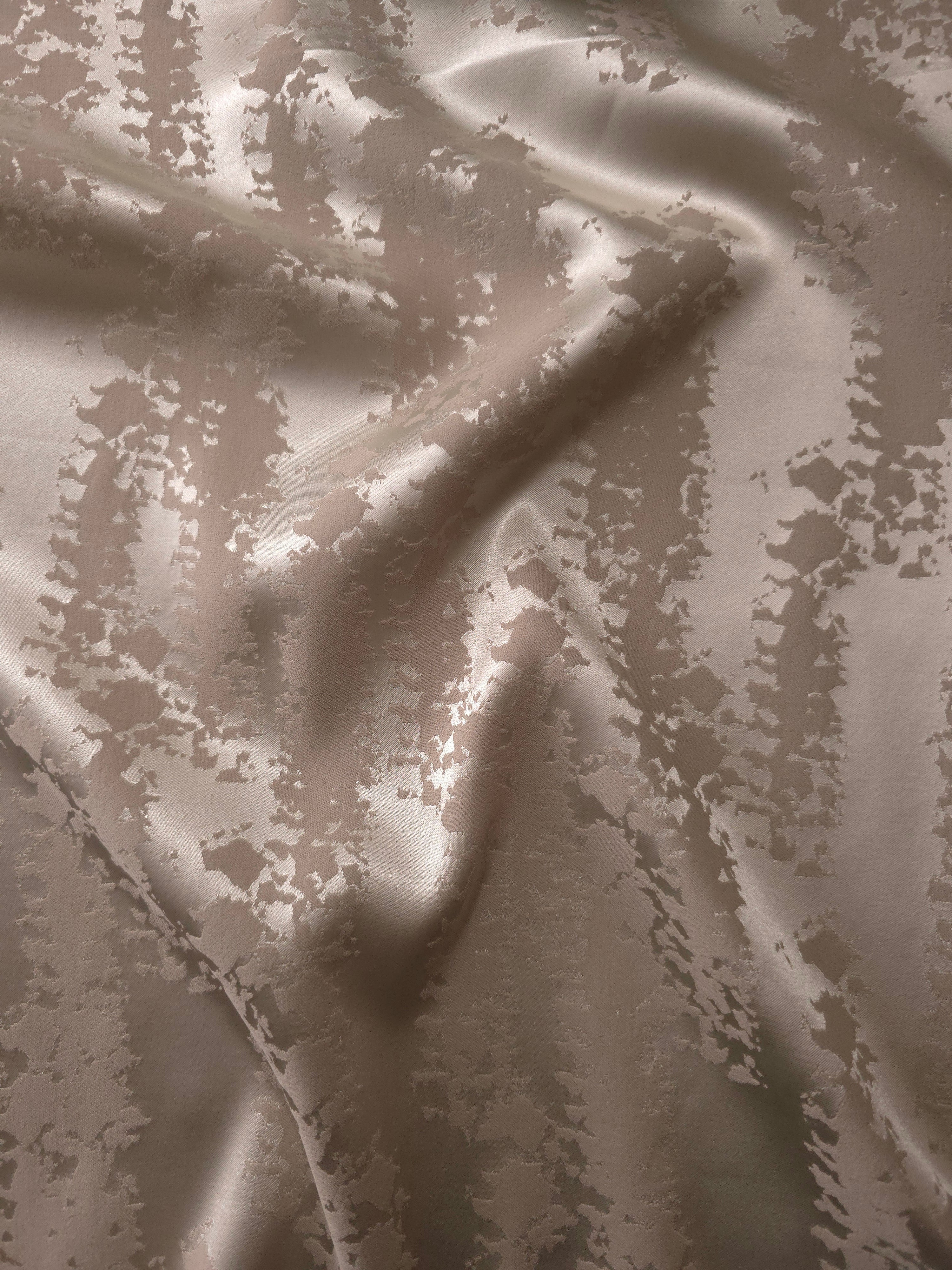 Taupe-beige satin folded gently, the animal print pattern reading mostly through subtle tonal sheen