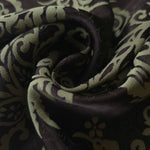 A tight fold in the brown satin, the baroque scrollwork bending sharply at the crease