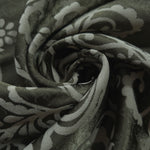 A soft crease in the olive satin, the scrollwork only emerging where the light catches the surface