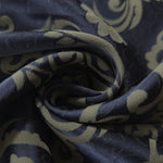 A tight fold in the navy satin, the olive-khaki scrollwork bending visibly at the crease