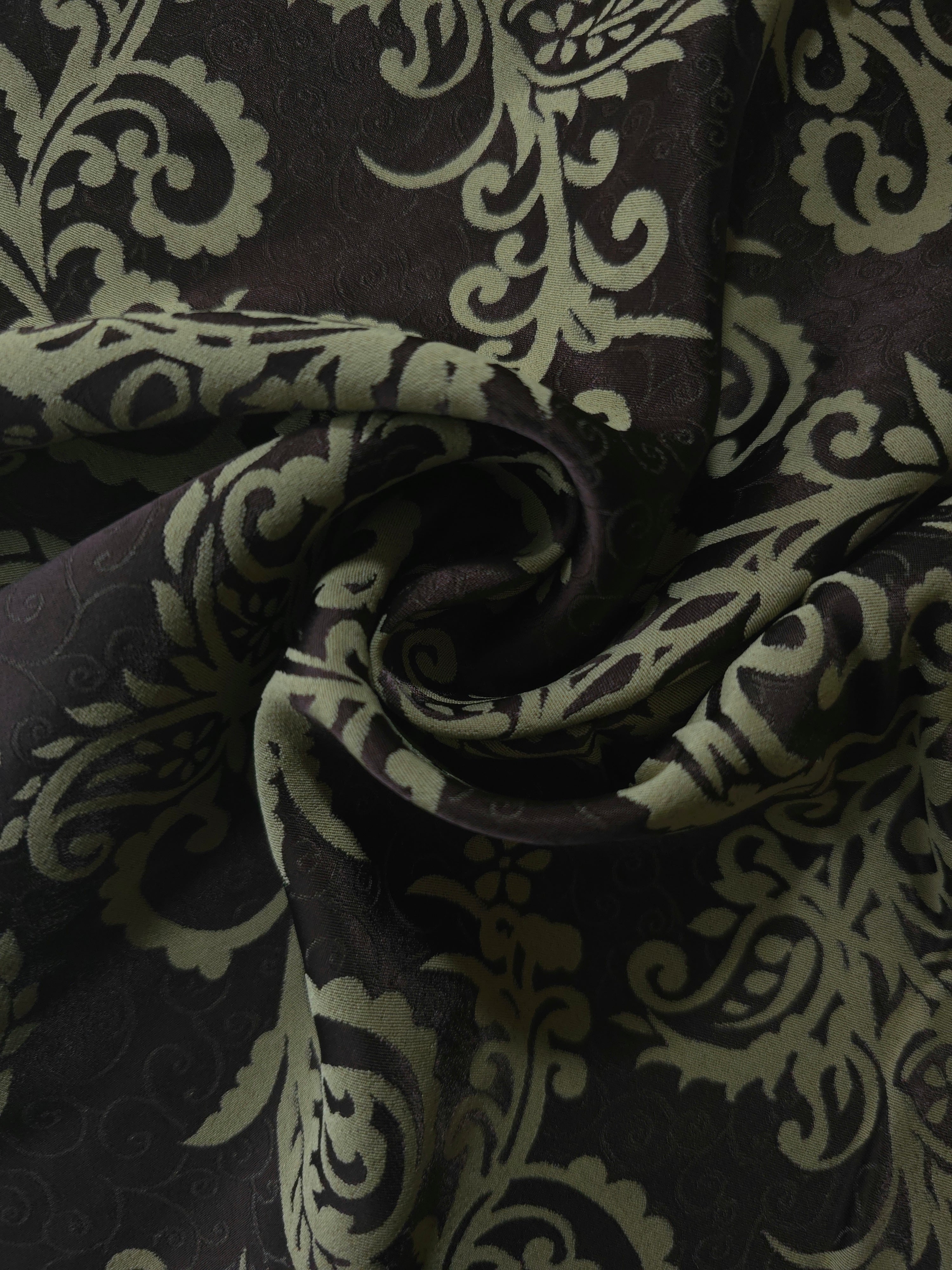 Brown baroque satin draped to catch the light, the ornate sage pattern visible across the fold