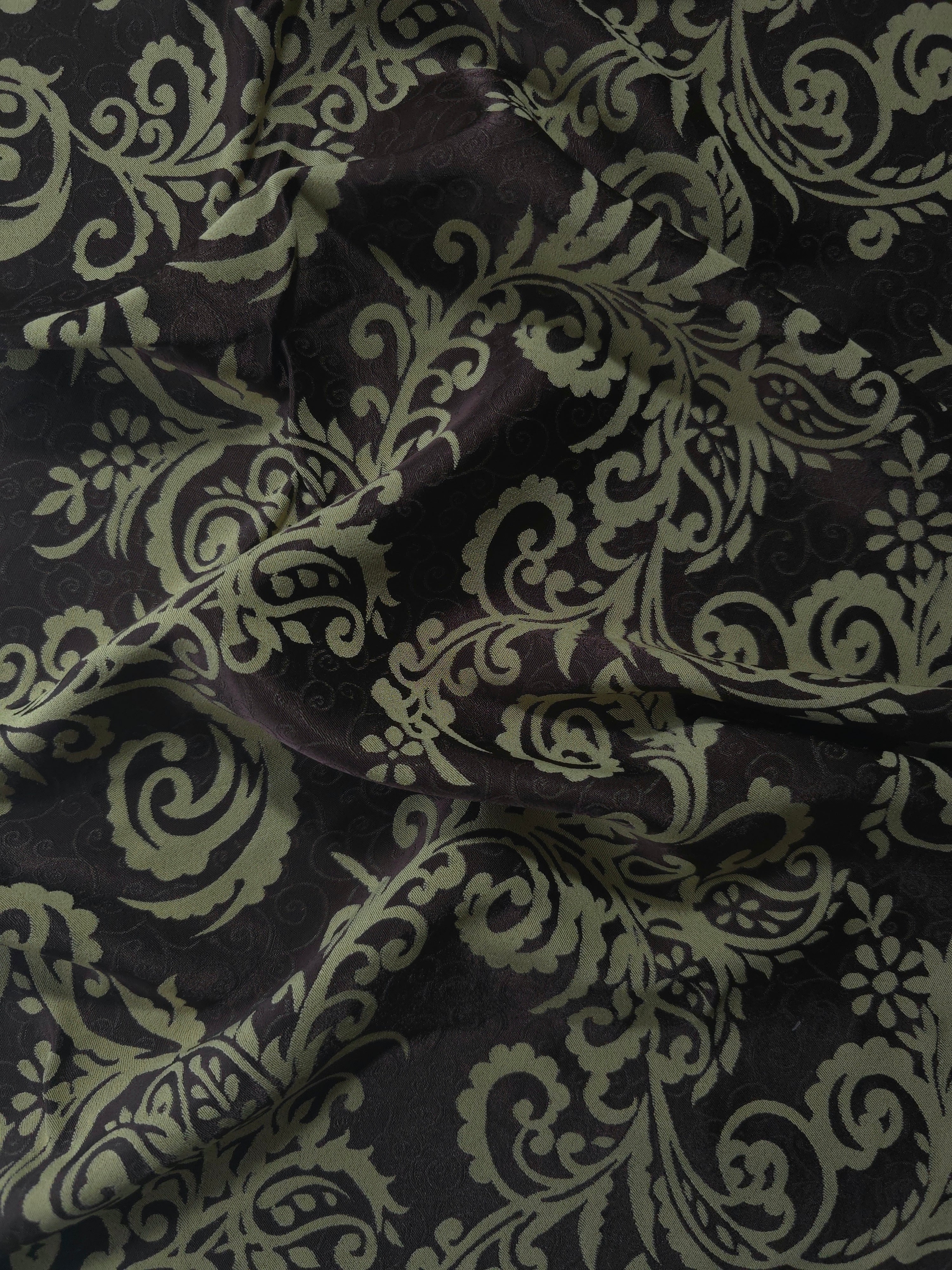 Deep brown satin folded over, the sage-green baroque scrollwork standing out boldly against the dark base