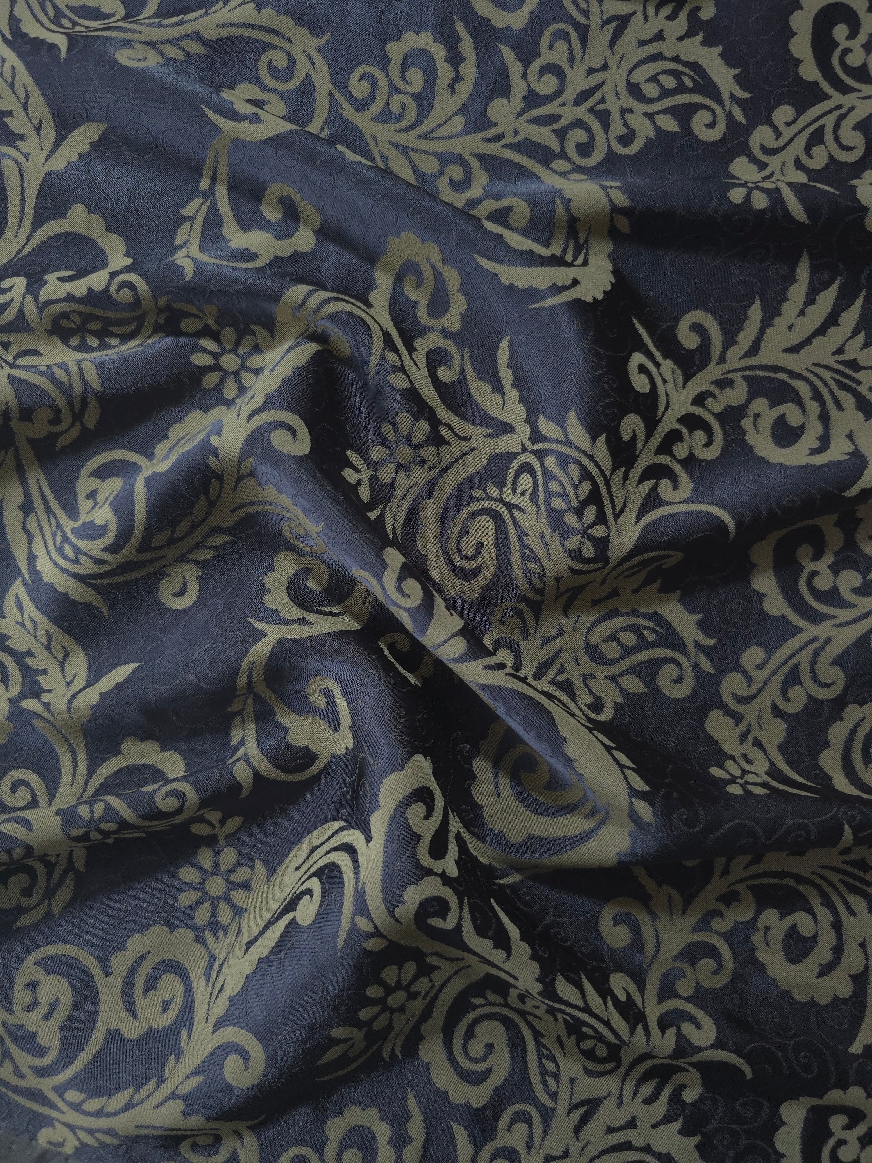 Navy satin folded over, the olive-khaki baroque scrollwork standing out warmly against the deep blue base