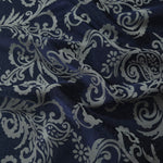 Navy satin folded over, the cool grey baroque scrollwork standing out crisply against the deep blue base