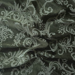 Olive green satin folded softly, the baroque scrollwork reading through tonal sheen rather than strong contrast
