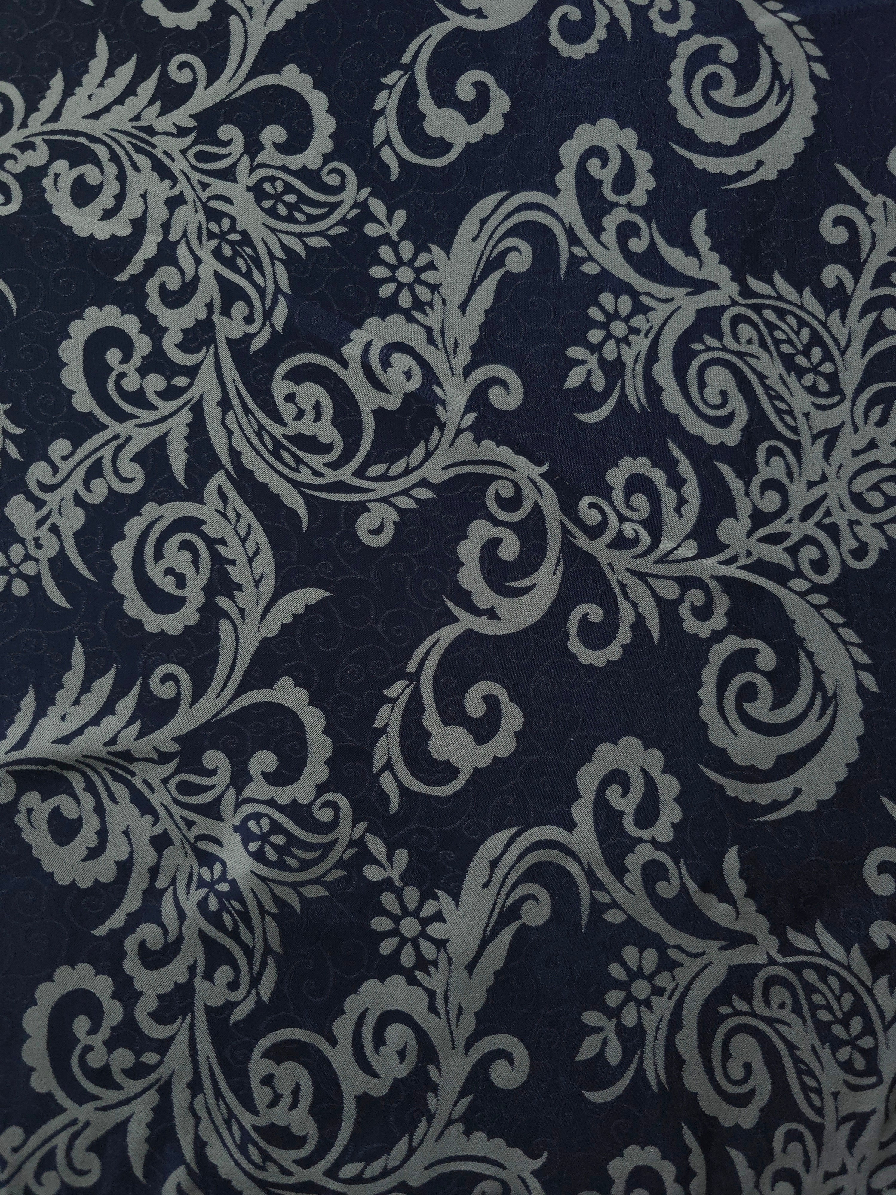 A wider view of the navy and grey baroque satin laid flat, showing the full scroll pattern repeat
