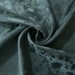 Teal floral satin draped in loose waves, the delicate tonal motif visible across the moving fabric