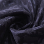Close drape of leopard metallic jacquard showing raised motif and soft folds.
