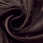 Close drape of dark brown metallic wave jacquard showing woven texture and shimmer.