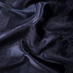 Wave fold of metallic wave motif jacquard showing controlled shimmer on woven fabric.