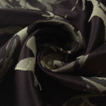 A tight fold in the black satin, the abstract pattern breaking sharply at the crease