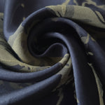 A tight fold in the navy-charcoal satin, the splatter pattern bending with the crease of the fabric