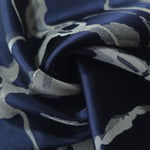 A soft crease in the navy satin, the fractured pattern bending unevenly with the fold