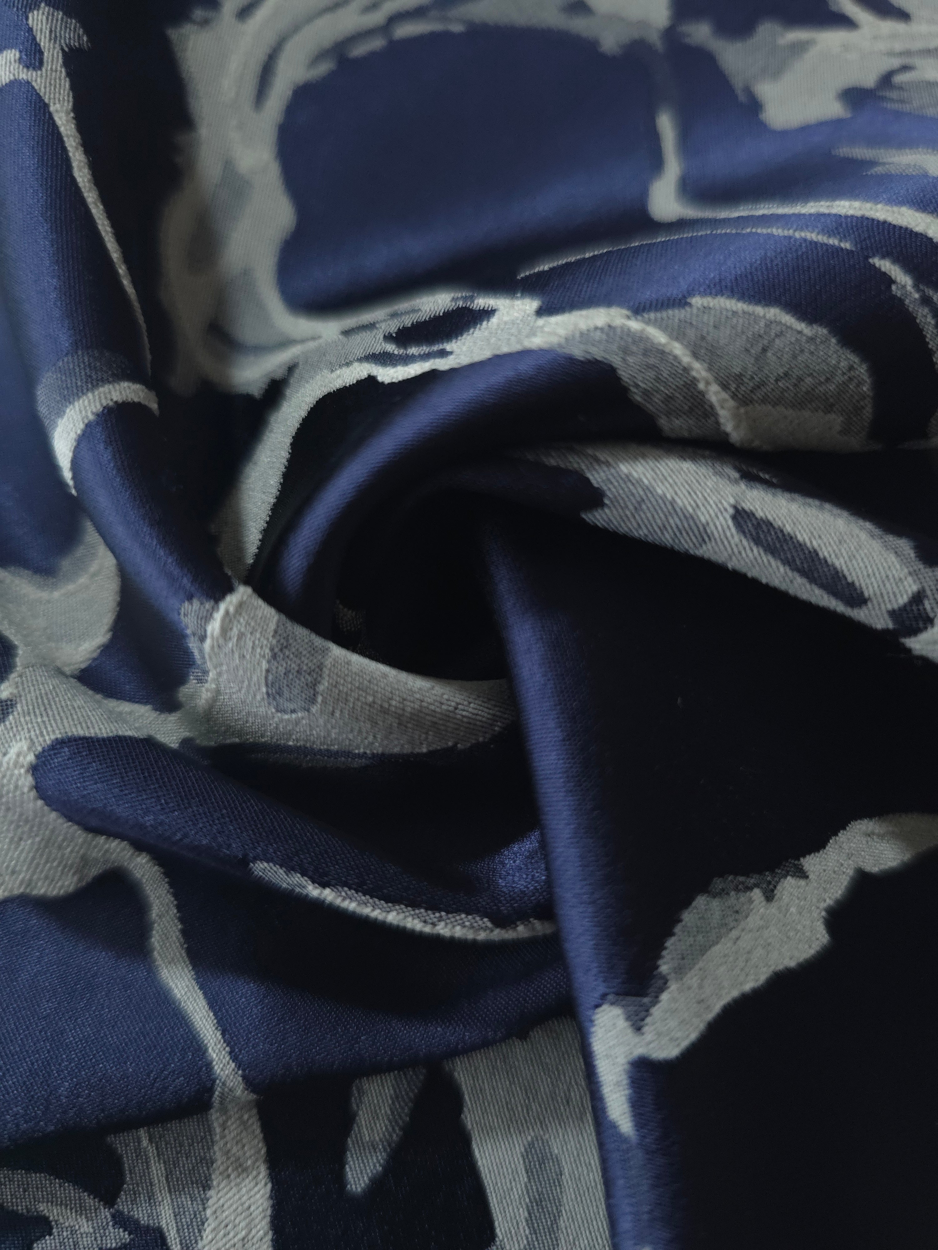 A soft crease in the navy satin, the fractured pattern bending unevenly with the fold