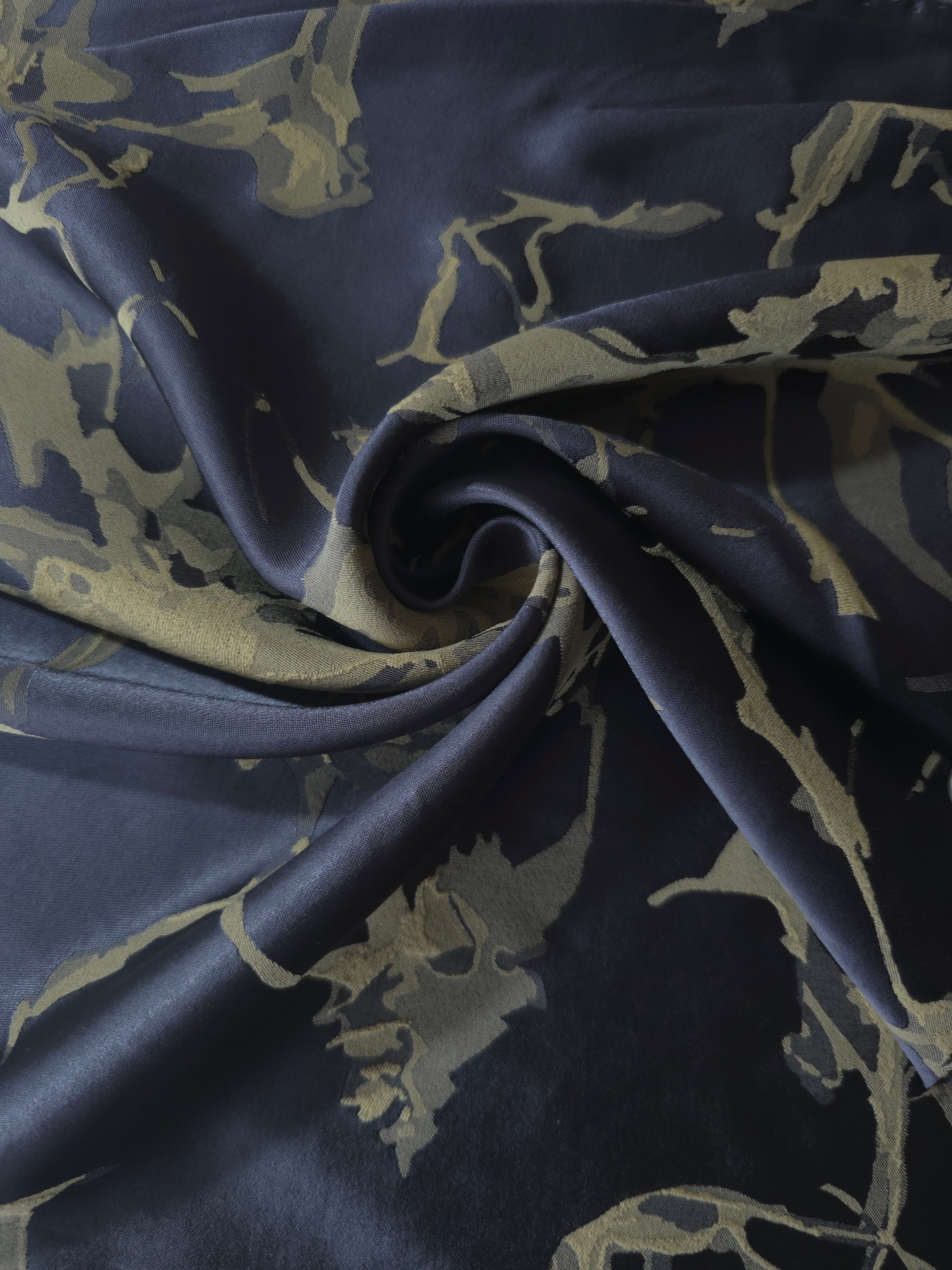 Navy-charcoal graphic line satin draped to show its glossy movement against the olive-tan splatter