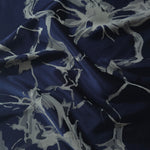 Navy satin folded softly, the grey-blue fractured line motif reading as branching abstract shapes