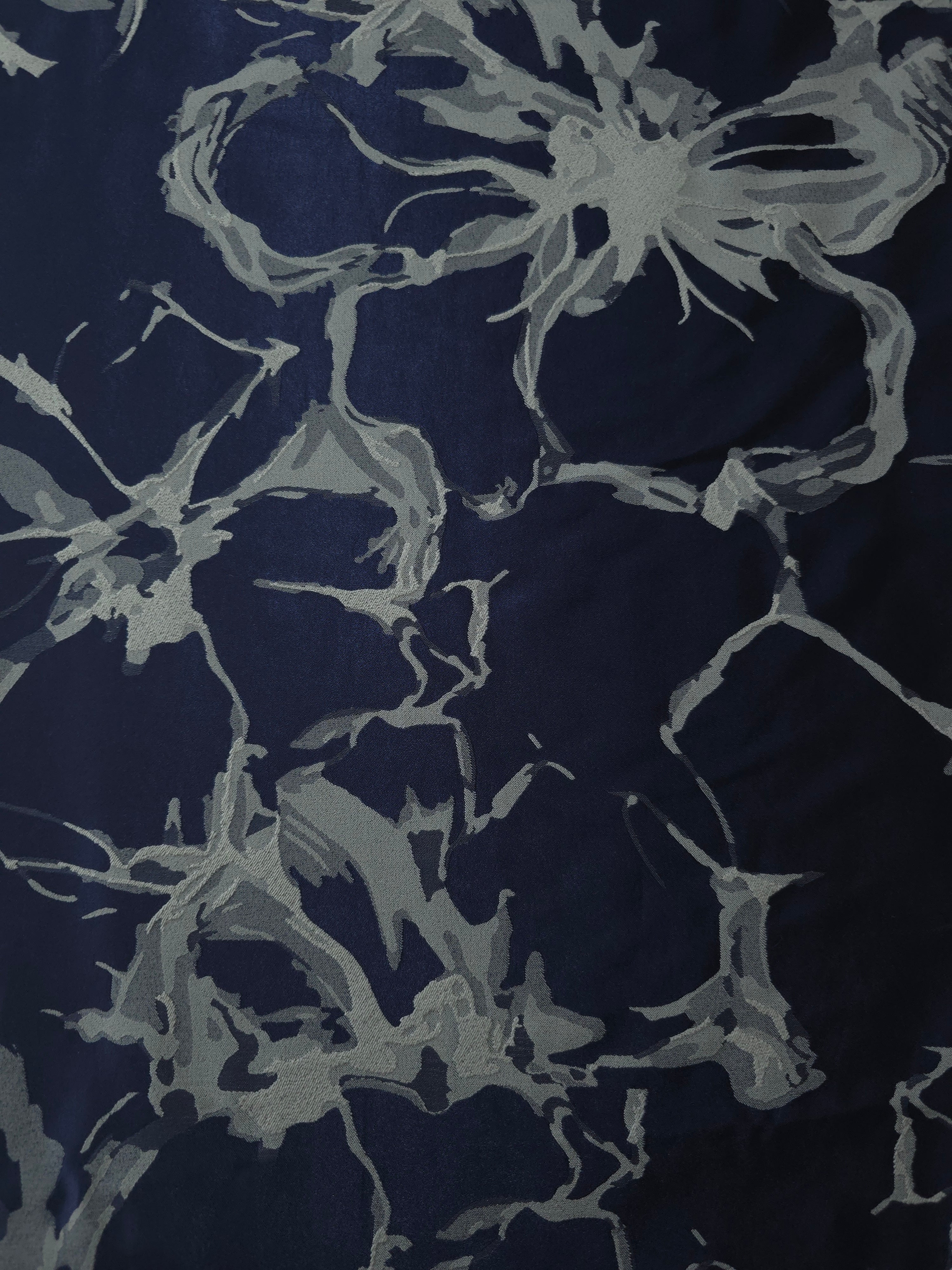 A wider view of the navy and grey-blue graphic line satin laid flat, showing the full abstract repeat