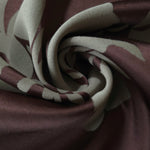 A tight fold in the wine satin, the hibiscus petal outline bending sharply at the crease
