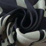 A soft crease in the black satin, the hibiscus outline breaking across the fold