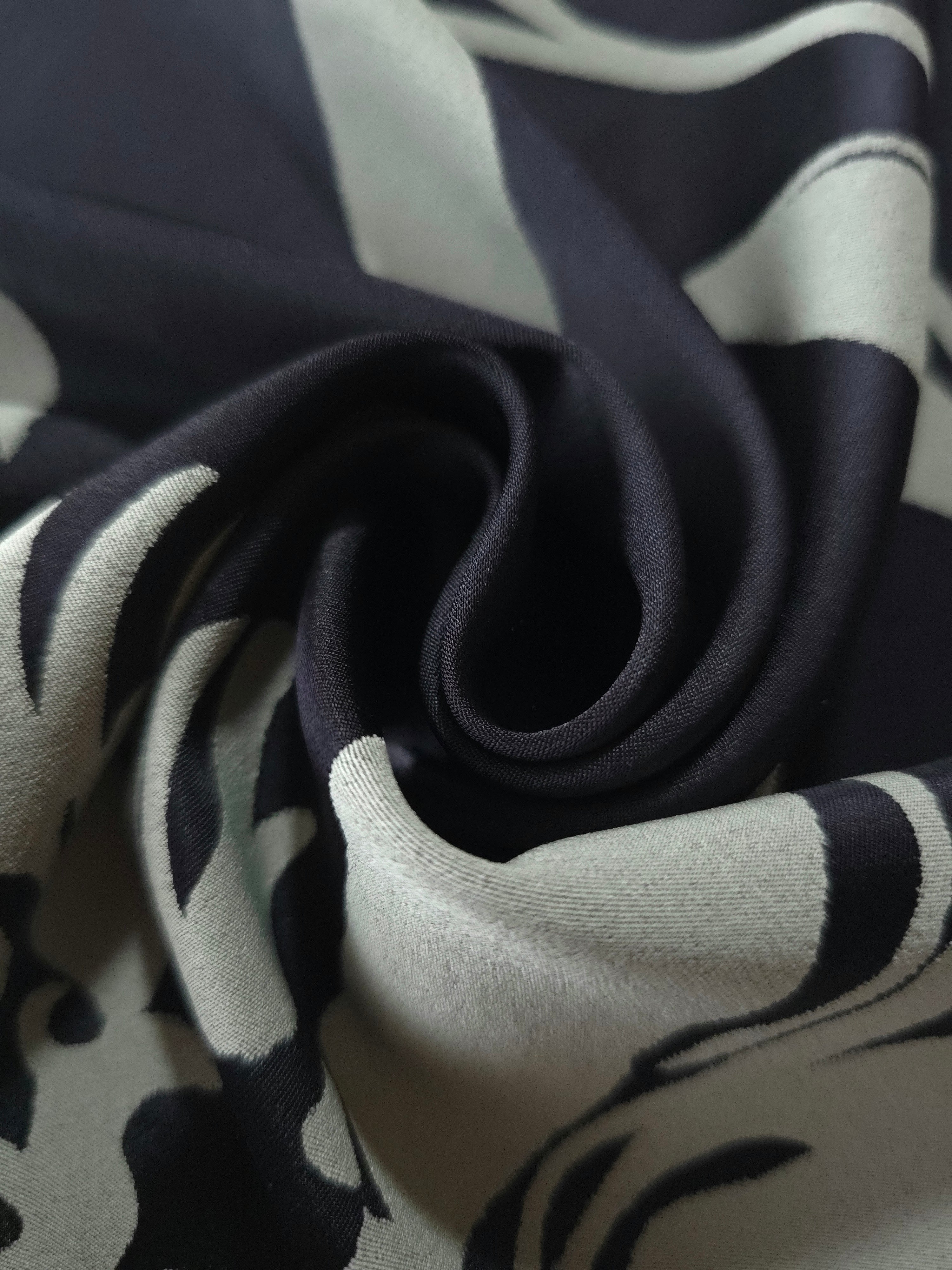 A soft crease in the black satin, the hibiscus outline breaking across the fold