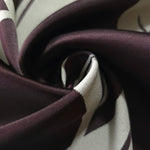 A tight fold in the eggplant satin, the petal outline bending with the crease of the fabric