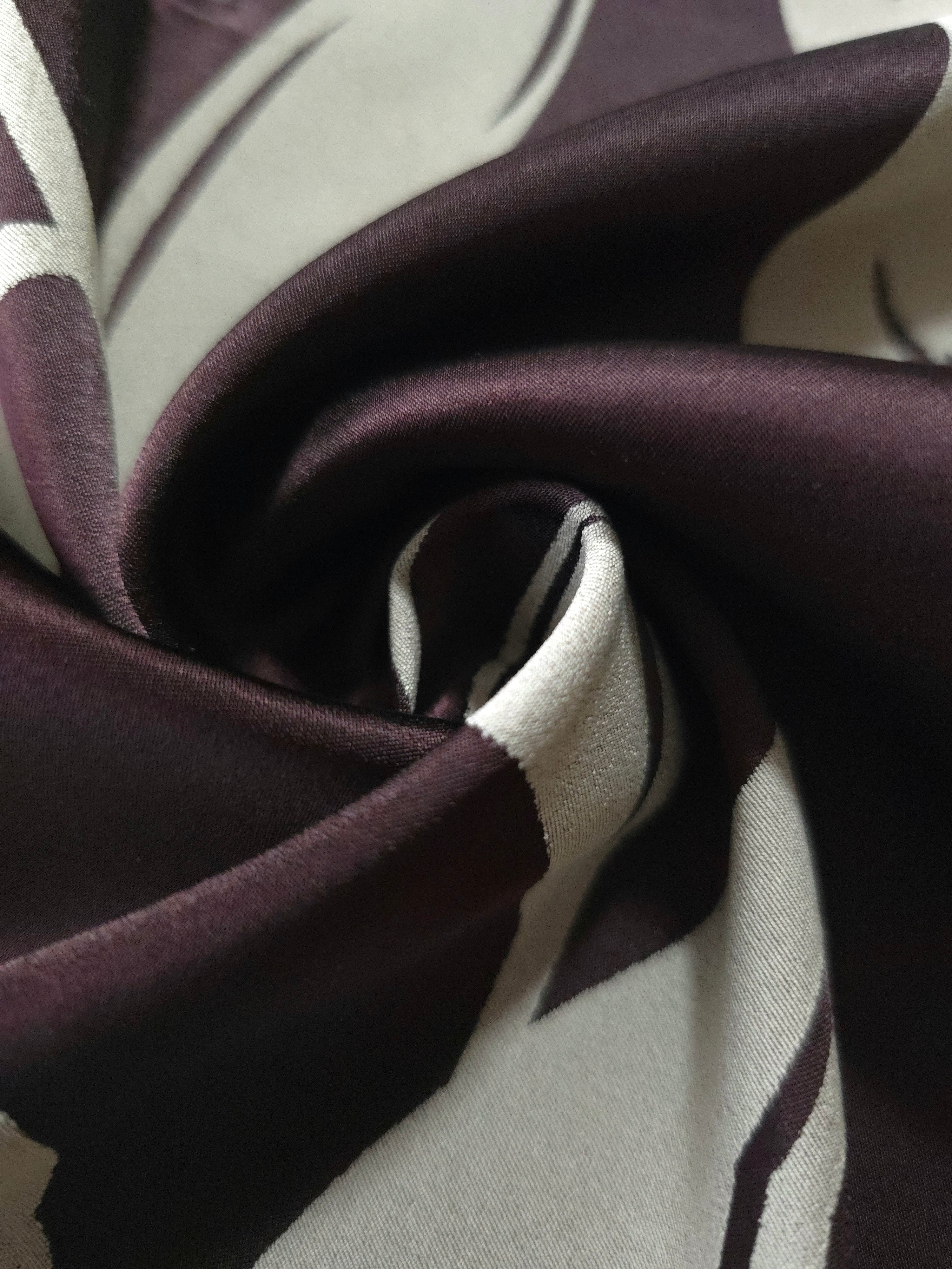 A tight fold in the eggplant satin, the petal outline bending with the crease of the fabric
