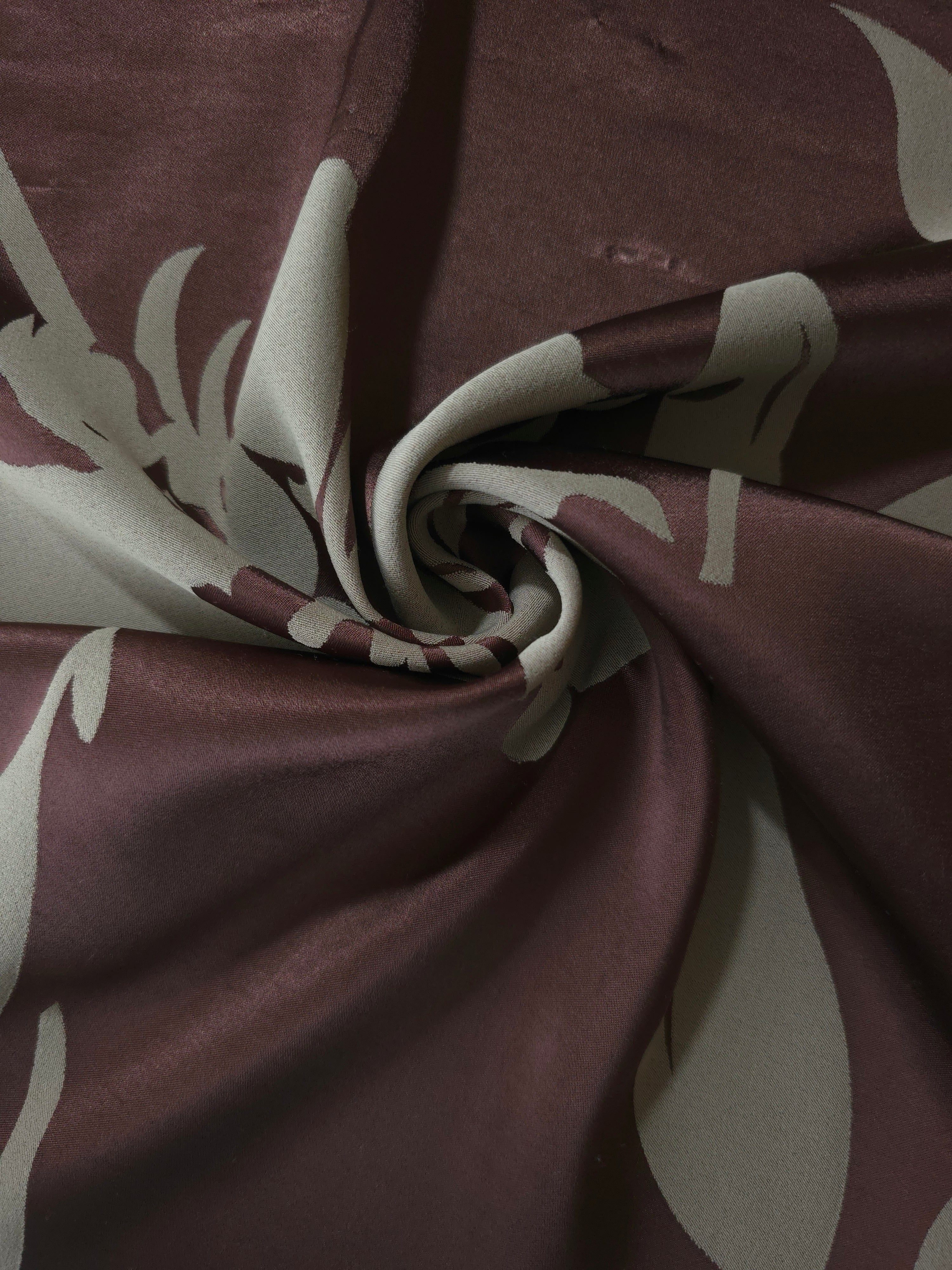 Wine hibiscus flower satin draped to catch the light, the bold petal shape visible across the fold