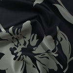 Black satin folded softly, the sage hibiscus petals reading crisply against the deep base