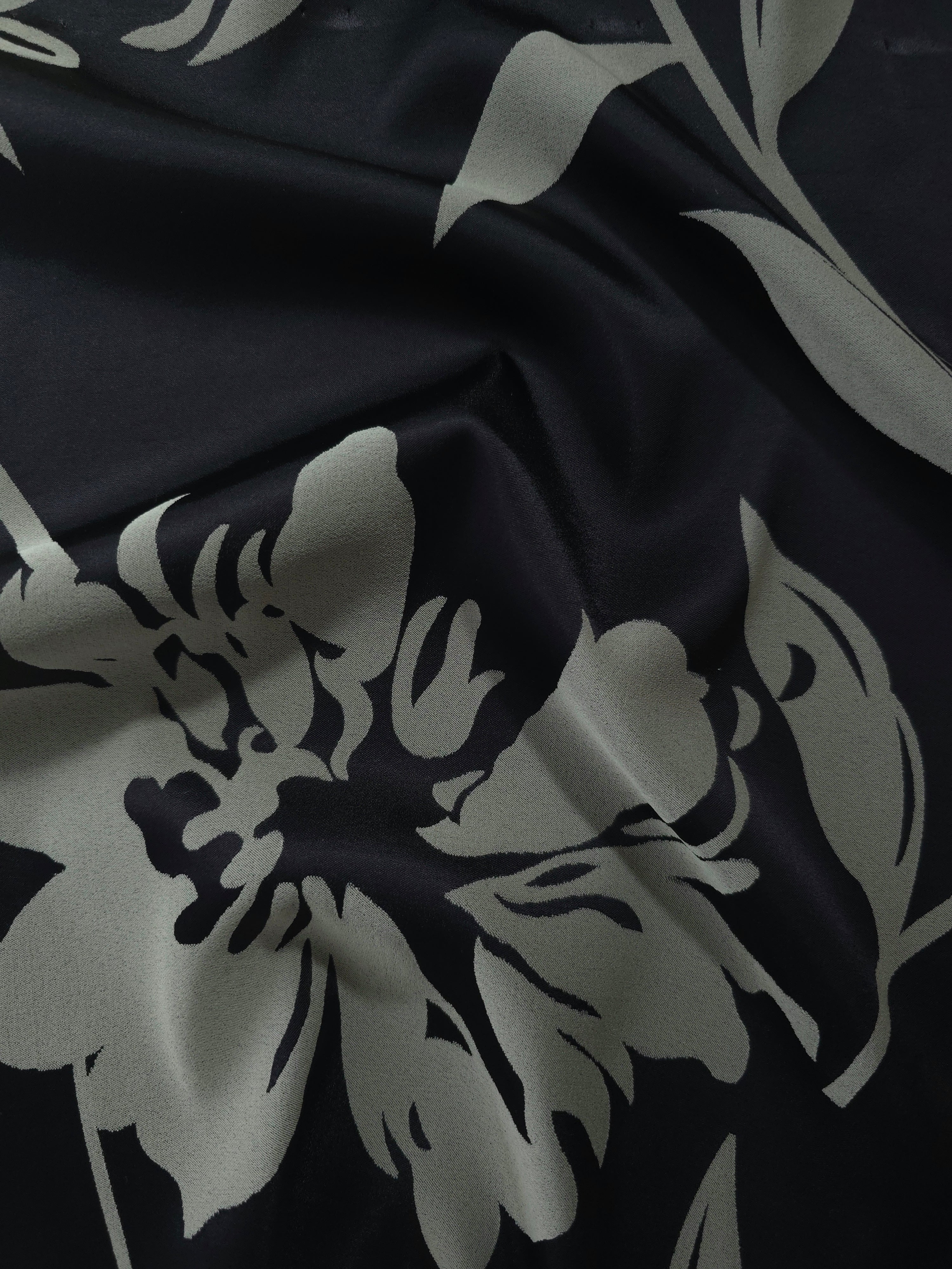 Black satin folded softly, the sage hibiscus petals reading crisply against the deep base
