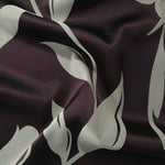 Deep eggplant satin folded over, the sage hibiscus petals standing out against the dark purple-black base