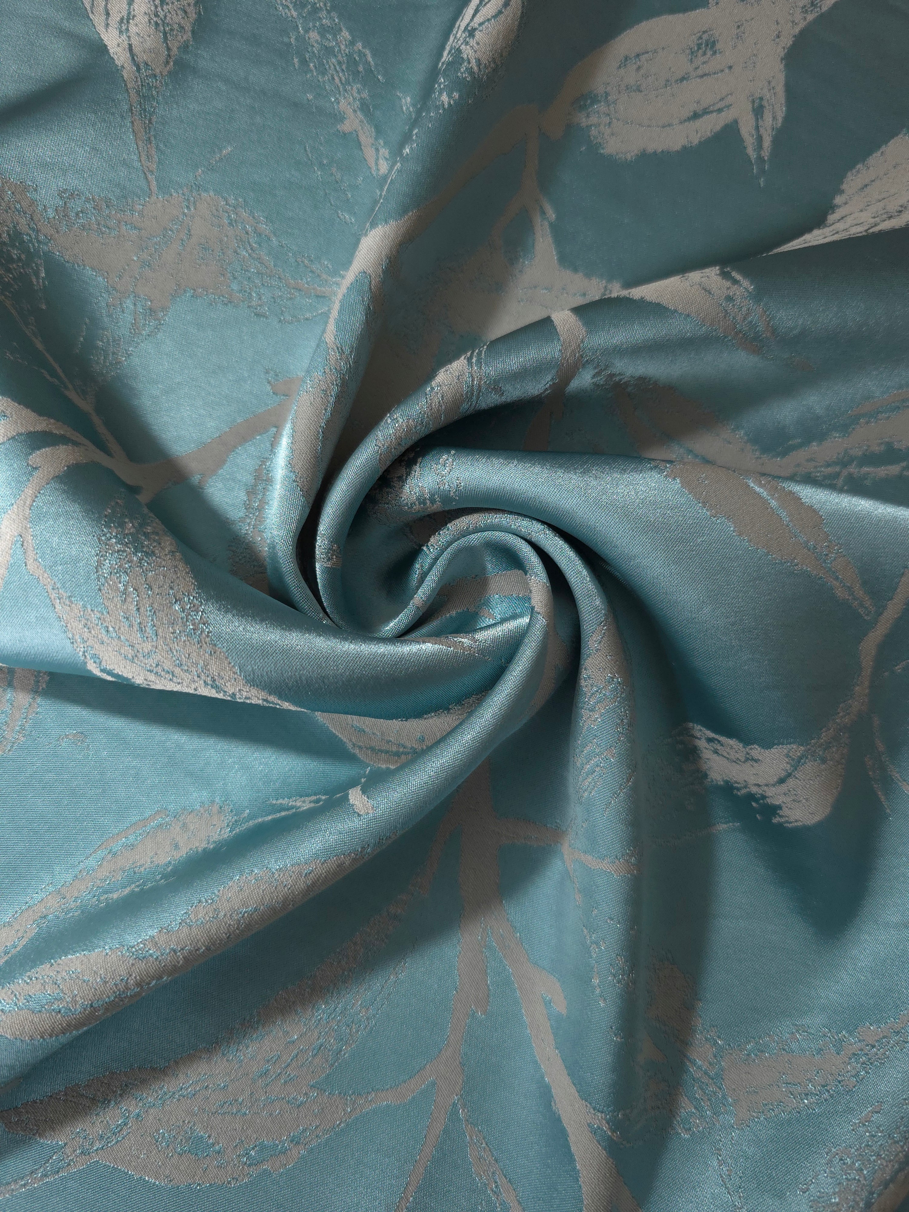 Teal leaf-pattern satin draped to show its glossy movement against the taupe branch motif
