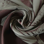 A tight fold in the maroon satin, the lily petal outline bending visibly at the crease