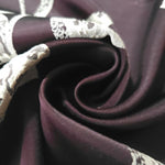 A tight fold in the plum satin, the speckled lily petal detail bending with the crease