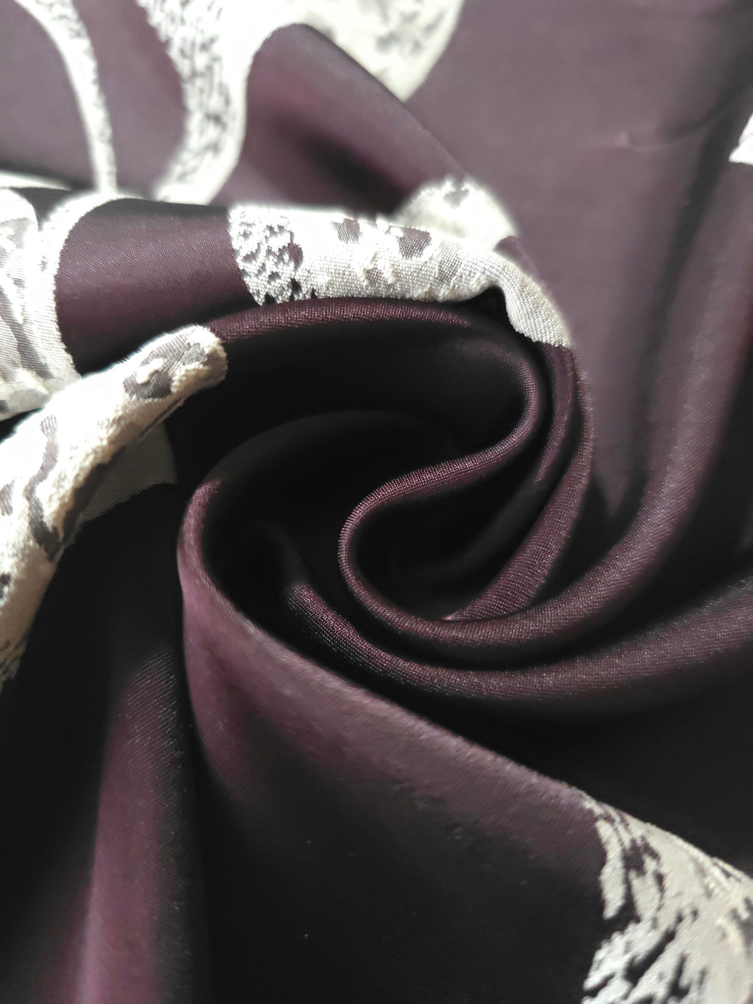 A tight fold in the plum satin, the speckled lily petal detail bending with the crease