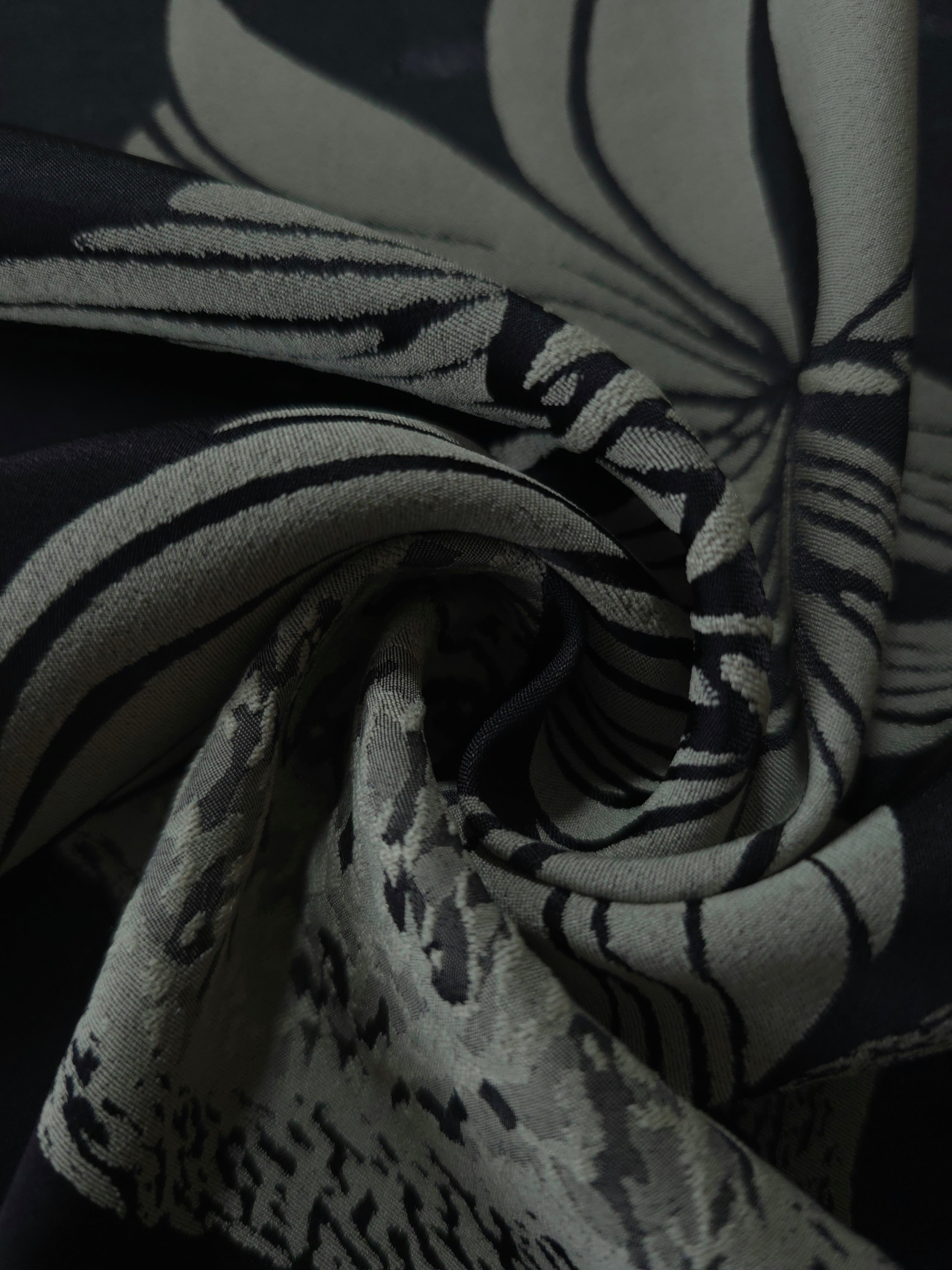 A soft crease in the black satin, the lily outline breaking across the fold