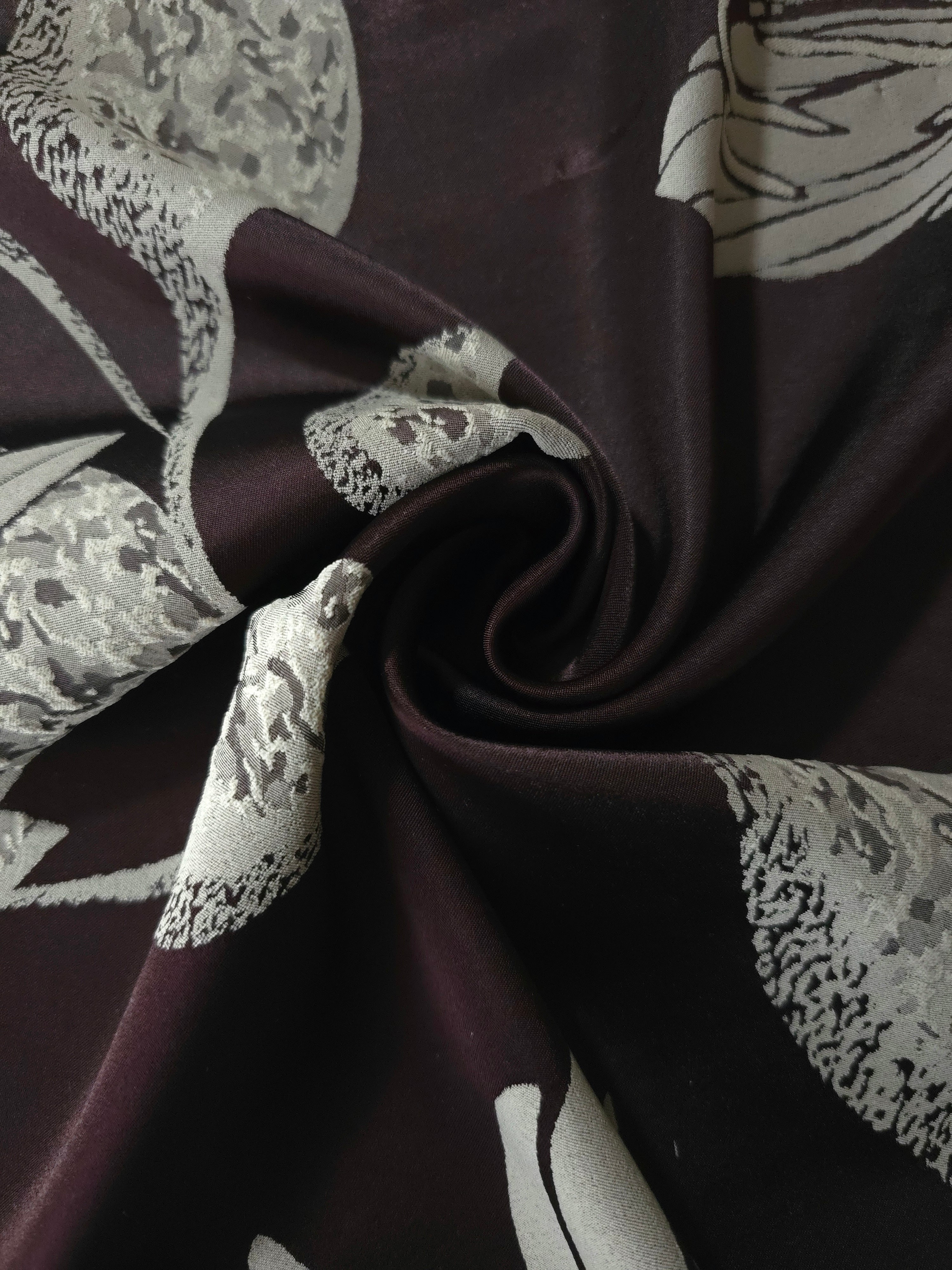 Plum lily flower satin draped to catch the light, the textured petal fill visible across the fold