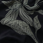 Black satin folded softly, the sage lily flower line art reading crisply against the deep base